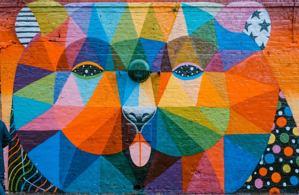 Vibrant geometric mural of a bear on a brick wall in London, showcasing diverse colors and artistic flair.